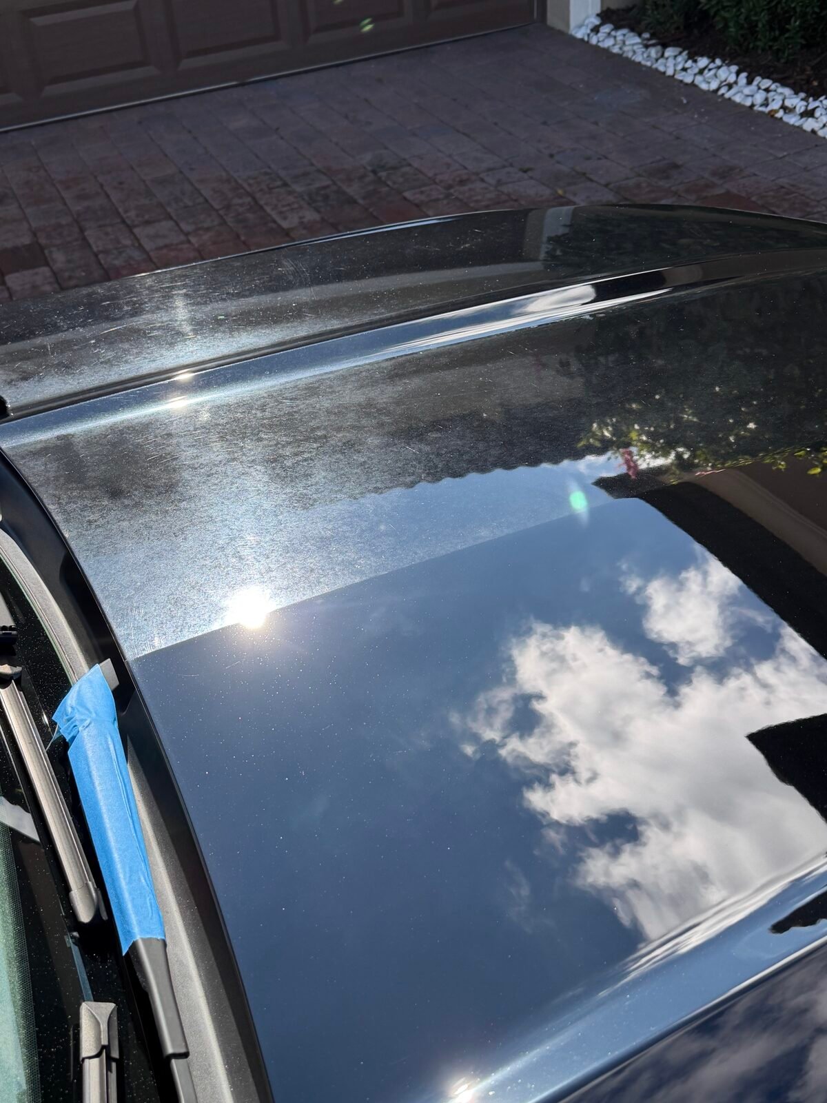 Close-up of paint correction in progress on a black vehicle roof